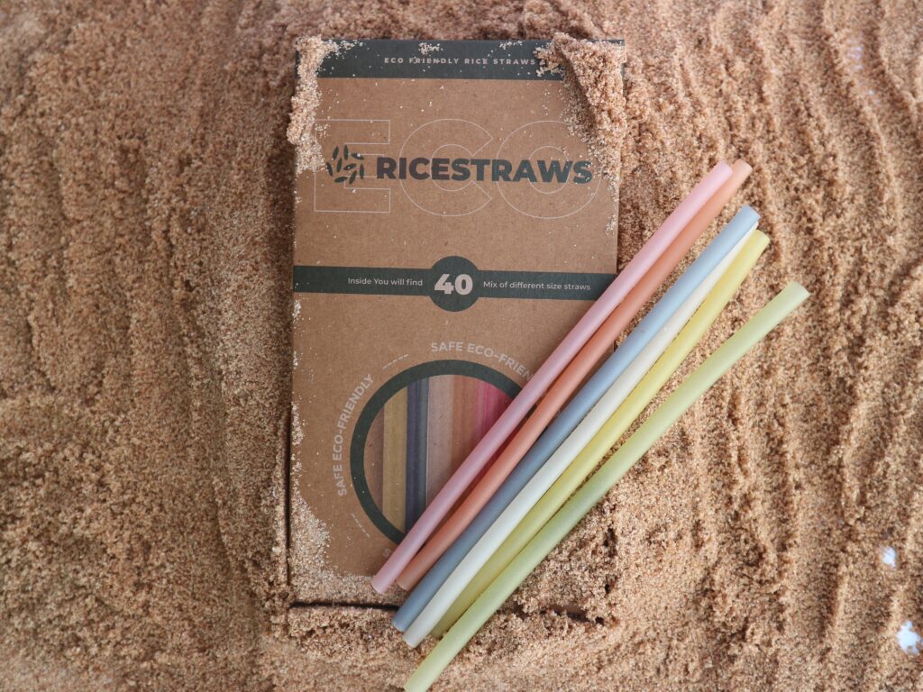 A box of RICESTRAWS with colourful rice straws lying on sand