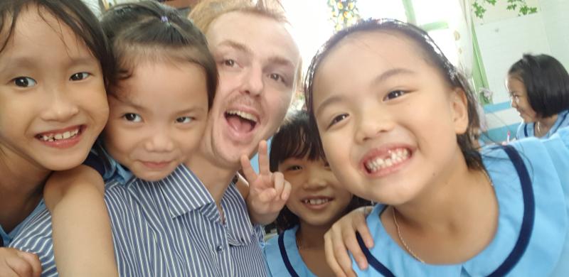 Dags taking a selfie with smiling young students in a classroom in Vietnam