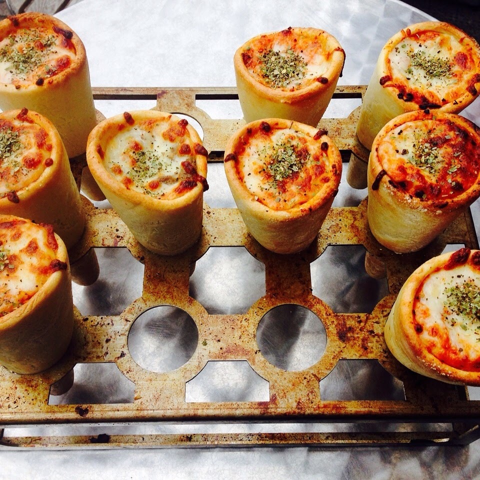 A tray of freshly baked pizza cones topped with melted cheese and herbs