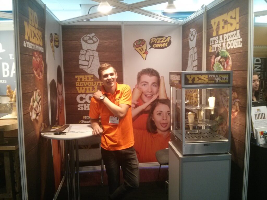 Dags at the Pizza Cones trade-show stand next to a heated display cabinet