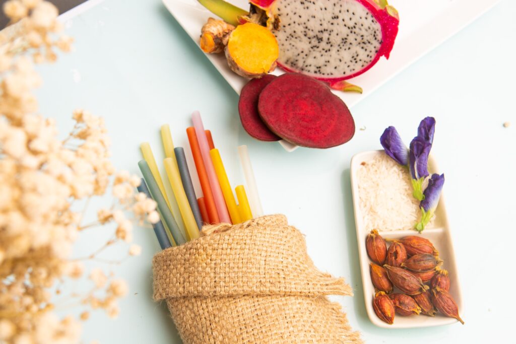 Colourful rice straws in a hessian wrap beside dragon fruit, beetroot, turmeric, rice and butterfly pea flowers